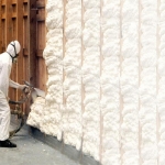 A man spraying on insulation to increase r-value